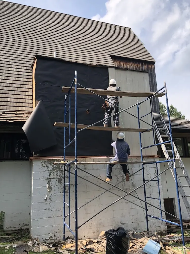 American Sons Roofing crew working on exterior siding and roof repairs